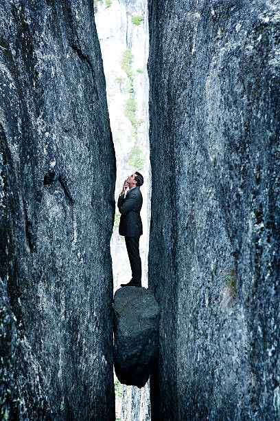 istock Businessman Standing On Rock Stuck In Deep Crevasse 637179288