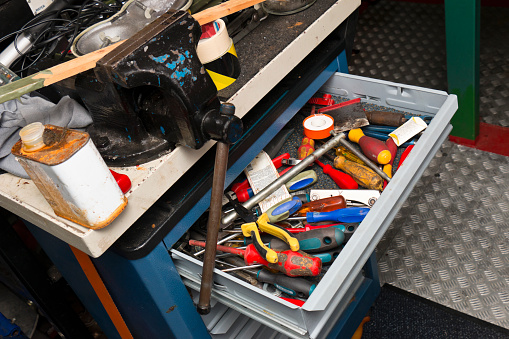 Vice and messy workbench with toolbox in an engine room of a ship.