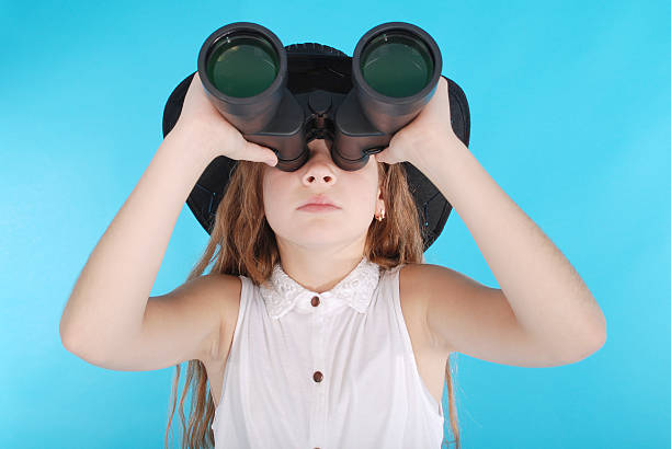 istock Young girl with binoculars looking up at copy space 637180966