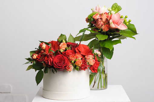 flower arrangement on table. Bouquet of roses in a paper box. vase in the background.
