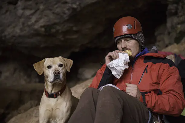 Man and dog in a cave.Pause for a meal.