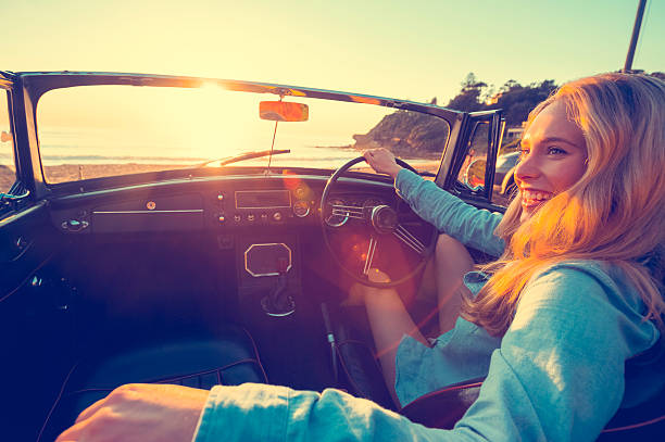 istock Woman driving a convertible at the beach. 637188196