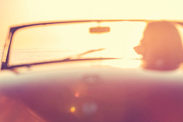 istock Woman driving a convertible at the beach. 637188246