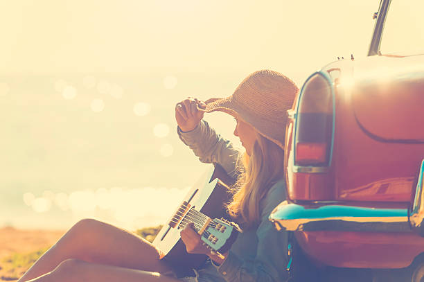 istock Woman with guitar leaning on a car. 637188726
