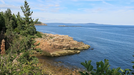 Picturesque scene in Acadia National Park Loop Road with forest,  Rocky Ocean Shore line, blue Water, Maine