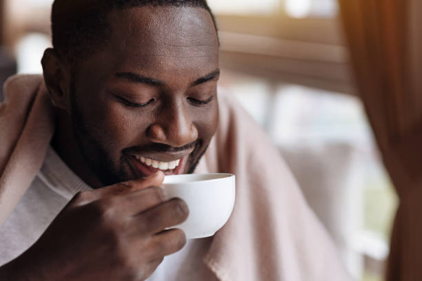 homem afro-americano encantado desfrutando da xícara de chá - drinking tea cup drink - fotografias e filmes do acervo
