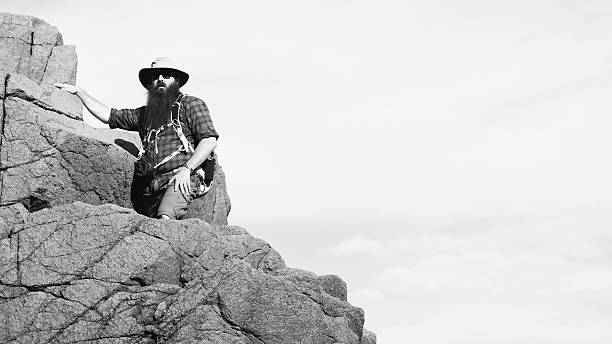 istock Bearded Man Wearing Hat Climbing Rocks, Black and White 637191384