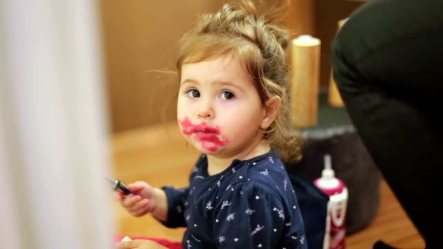 Baby girl playing with makeup and mimic her mom