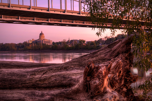 Missouri River, a bridge, a tree stump, and Capitol Building during sunset in Jefferson City, Missouri.