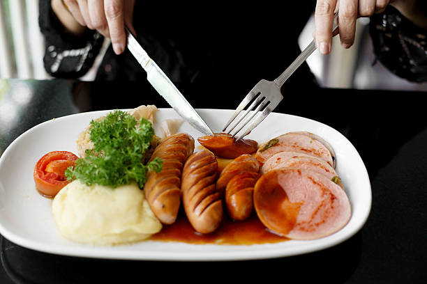 woman hands holding knife and fork during eating sausage