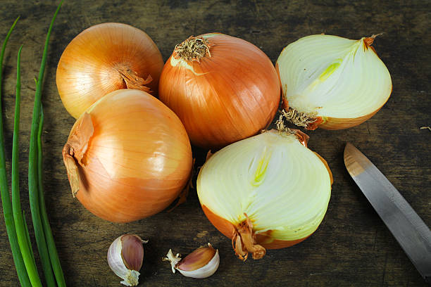 istock Whole and sliced onions on wooden cutting board 637196288