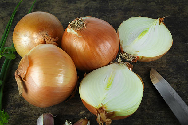 istock Whole and sliced onions on wooden cutting board 637196324