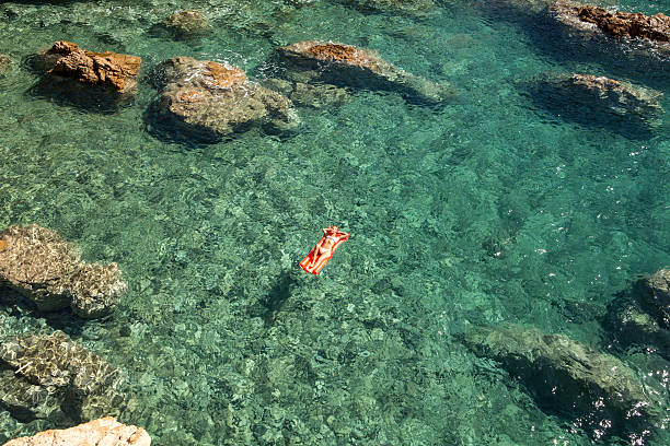 코브 이탈리아에서 떠다니는 매트리스에서 휴식을 취하는 젊은 여성 - pool raft sea red floating on water 뉴스 사진 이미지