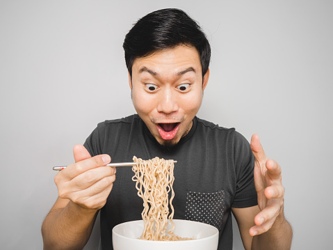 Asian man feel surprise with how delicious instant noodle is.