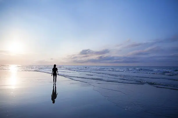 Photo of Woman walking on beach at sunrise