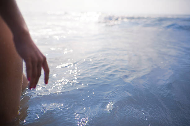 istock Woman's legs and hand standing looking at ocean 637201866