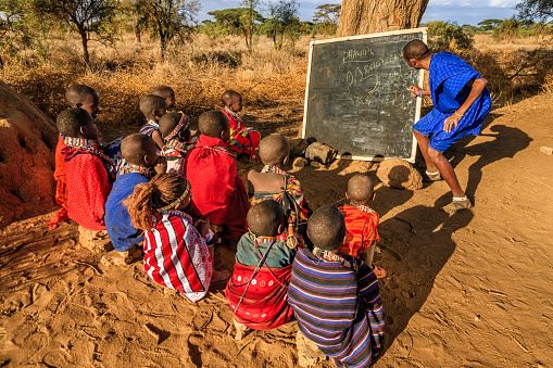 African children  from Maasai tribe during classes under the acacia tree in remote village, Kenya, East Africa. Maasai tribe inhabiting southern Kenya and northern Tanzania, and they are related to the Samburu.