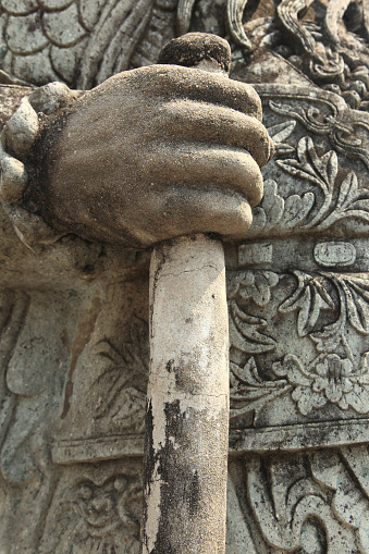 Closeup of a rock sculpture of a hand holding a long sword.