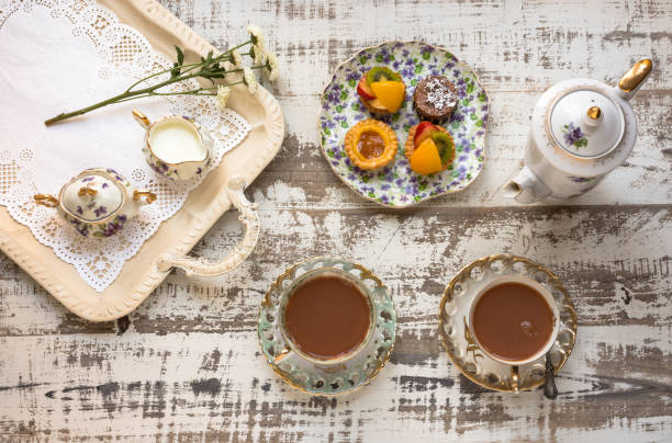 чайные чашки и фруктовые пироги, выложенные на деревенском столе - afternoon tea china antique cup стоковые фото и изображения