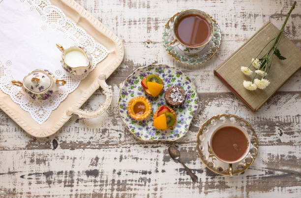 istock Tea cups and fruit tarts laid out on rustic table 637207116