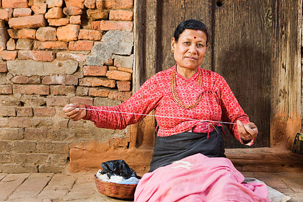 An elderly lady, approximately 60 years old, comfortably dressed, a craftswoman by profession, is in her factory where she weaves handcrafted looms with the help of a wooden maquila