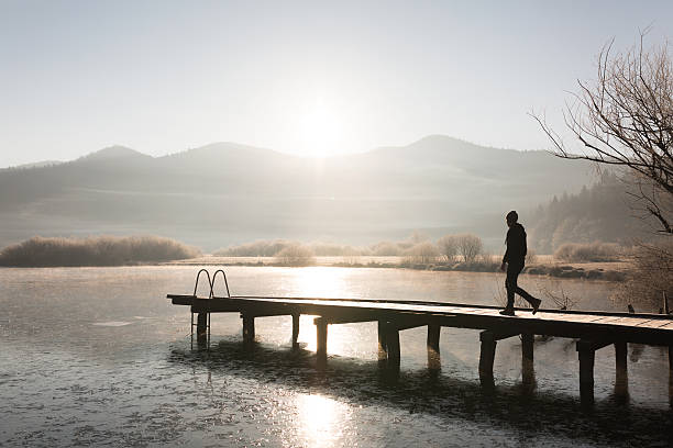 Lonesome man on vacation walks on a jetty at sunrise stock photo