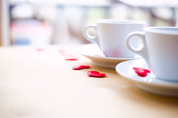 Couple white cups decorated by red hearts on wooden table. Valentine's day celebration concept. Copyspace.