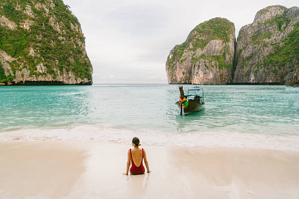 Woman on Maya Bay beach Young Caucasian woman sitting on Maya Bay beach in Krabi, Thailand phi phi le stock pictures, royalty-free photos & images