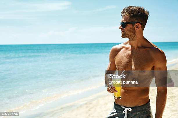 Foto de Verão Homem Musculoso Atlético Bebendo Coquetel De Suco Na Praia e mais fotos de stock de Praia