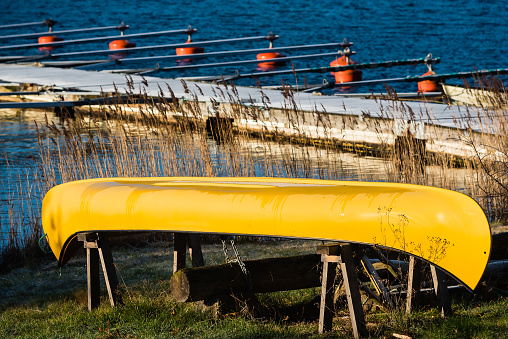 Overturned yellow canoe on stilts with marina in background.