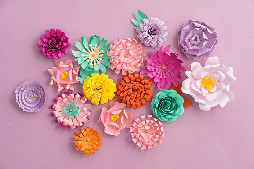 Colourful handmade paper flowers on pink background