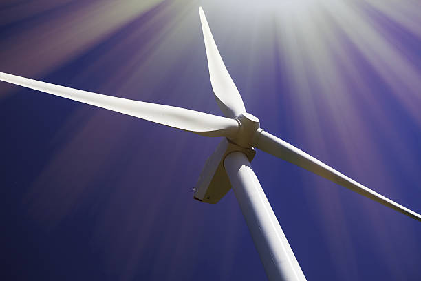 Solar and wind power. Turbine in bright sunshine. Solar and wind power. Turbine in bright sunshine. Close up of wind turbine rotor and blades in the bright sun and contrasting with plain blue sky. airfoil photos stock pictures, royalty-free photos & images