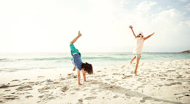 Shot of two excited young children doing cartwheels on the beach