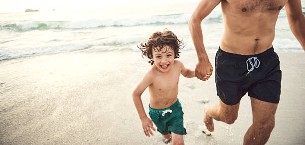 godersi una giornata con papà in spiaggia - surfing beach family father foto e immagini stock