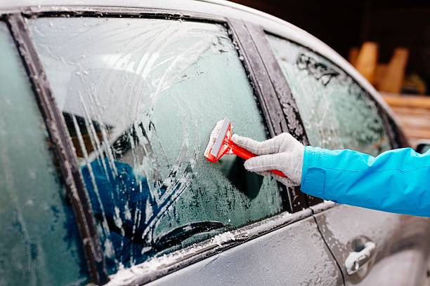 스크레이퍼로 사이드 카 앞 유리를 해독하는 여성 - snow car window ice scraper 뉴스 사진 이미지