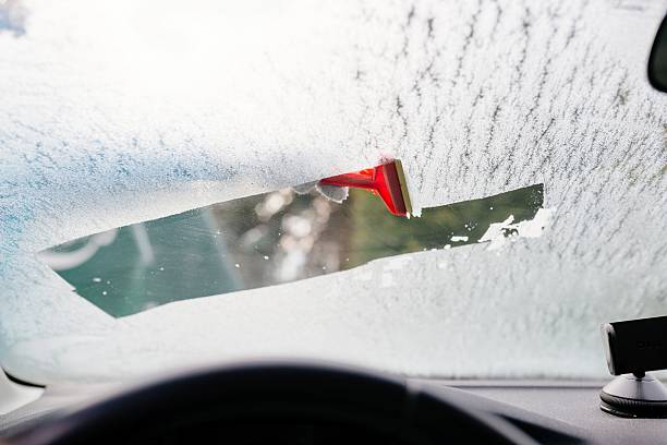 frau enteist vorderwagen-windschutzscheibe mit schaber - eiskratzer stock-fotos und bilder