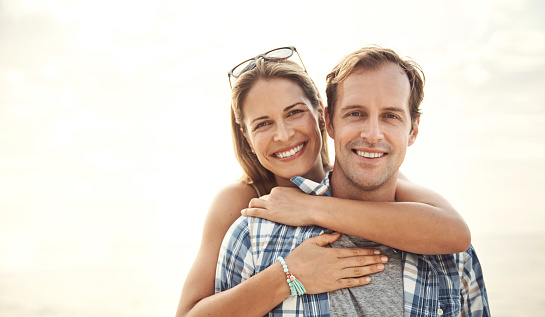 Portrait of a smiling mature couple embracing at the beach at sunset