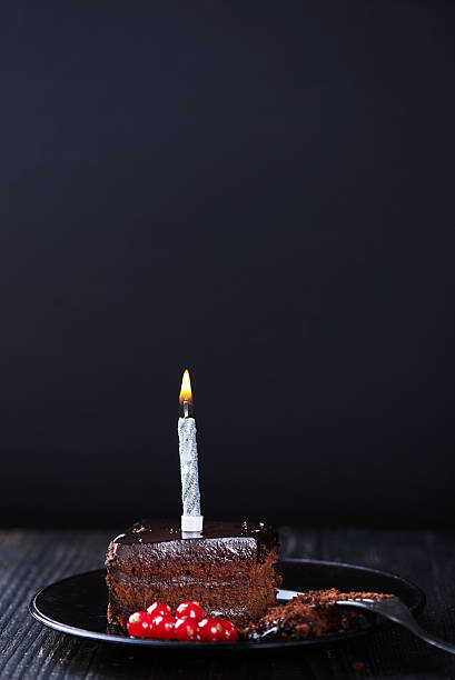 istock Slice of chocolate cake with a single lit candle. 637233280
