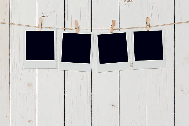 cuatro marcos de fotos en blanco colgados sobre fondo de madera blanca - 4 string fotografías e imágenes de stock