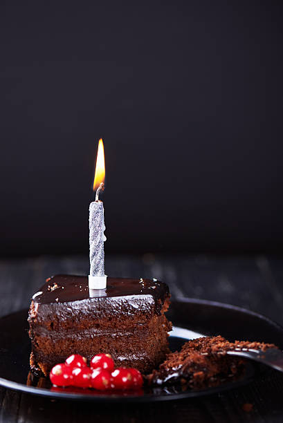 istock Slice of chocolate cake with a single lit candle. 637233462