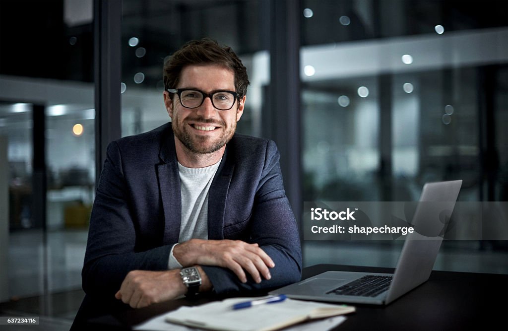 Doing it for the love of success Portrait of a happy young businessman working at his office desk Businessman Stock Photo