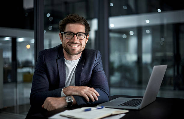 Doing it for the love of success Portrait of a happy young businessman working at his office desk looking at camera stock pictures, royalty-free photos & images