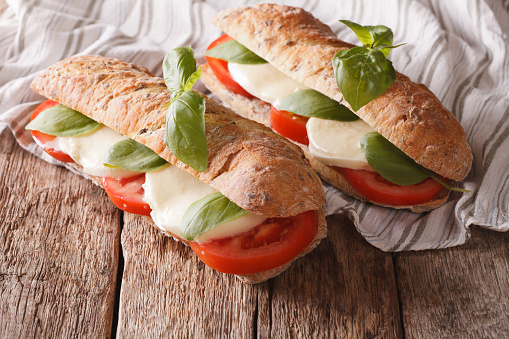 Italian sandwiches with fresh tomatoes, mozzarella cheese and basil close-up on the table. horizontal