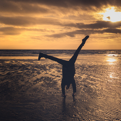 A Girl Does A Cartwheel On The Beach At Sunset