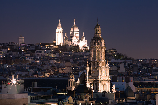 Aerial view of Sacre-Coeur Basilica or Basilica of the Sacred Heart of Jesus at the butte Montmartre and Saint Trinity church at night, Paris, France