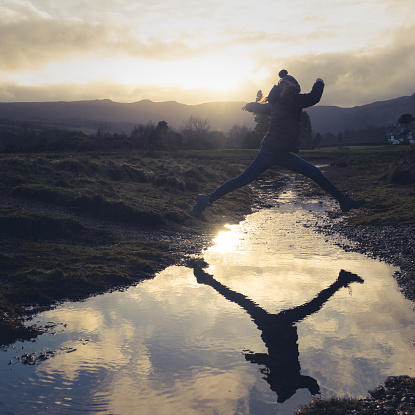 A Teen Jumps Over Water On A Nature Hike