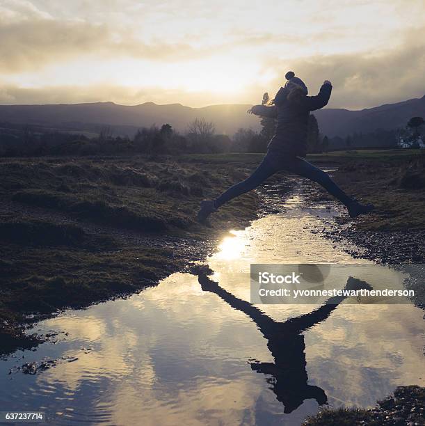 Girl Leaps Over Stream Stock Photo - Download Image Now - Jumping, Above, Stream - Body of Water