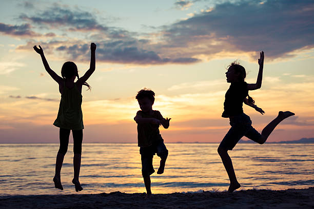 istock Happy children playing on the beach at the sunset time. 637238358