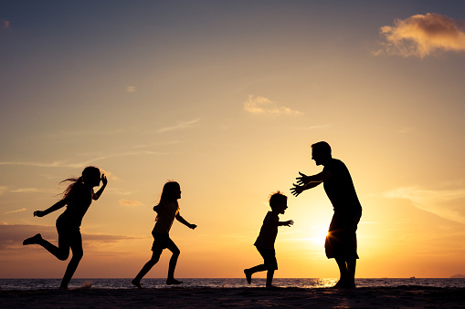 Father and children playing on the beach at the sunset time. Concept of friendly family.Father and children playing on the beach at the sunset time. Concept of friendly family.