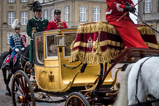Copenhagen, Denmark - January 04, 2017: A smiling Queen Margrethe in her 24-carat golden coach escorted by the Guard Hussar Regiment is arriving at Amalienborg Palace